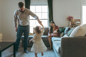 A family playing together in their living room with natural light streaming through the window.