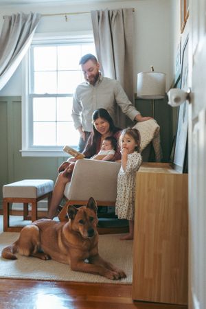 A family and their German Shepherd dog relax together in a cozy living room with natural light.
