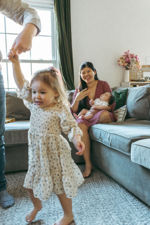 A joyful family moment in a cozy living room with a blue couch, green curtains and floral decorations.