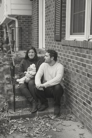 Black and white photo of family sitting on brick porch steps surrounded by fallen autumn leaves.