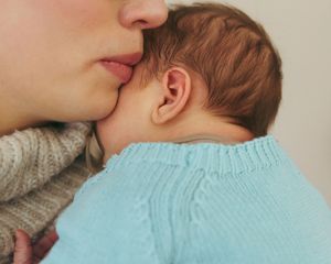 A close-up shot shows gentle affection and bonding with a baby wearing a mint green sweater.