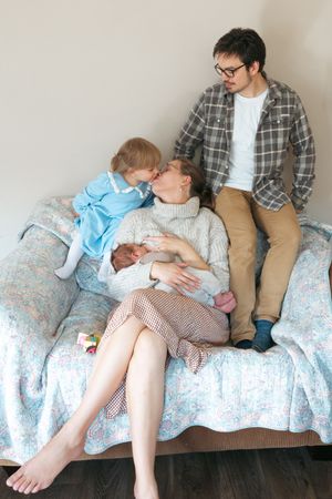 A series of four connected photos showing tender moments of rest and bonding on a floral patterned couch.