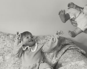 Vintage black and white photograph of a playful moment on a floral patterned couch.