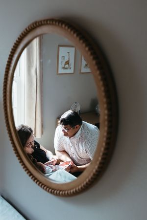 A sequence of mirror reflections showing tender moments between two people in a room with a round framed mirror.