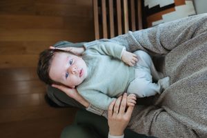 Person lying on wooden floor wearing mint green sweater and grey blanket in multiple poses.