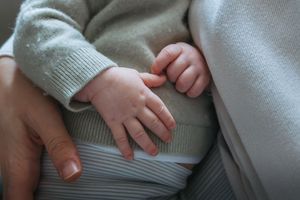 Close-up view of hands resting on a light gray textured surface showing tender interaction between two people.