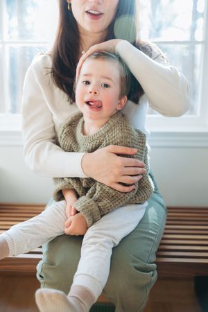 A sequence of joyful moments between a baby in a knit sweater and caregiver in a white top.