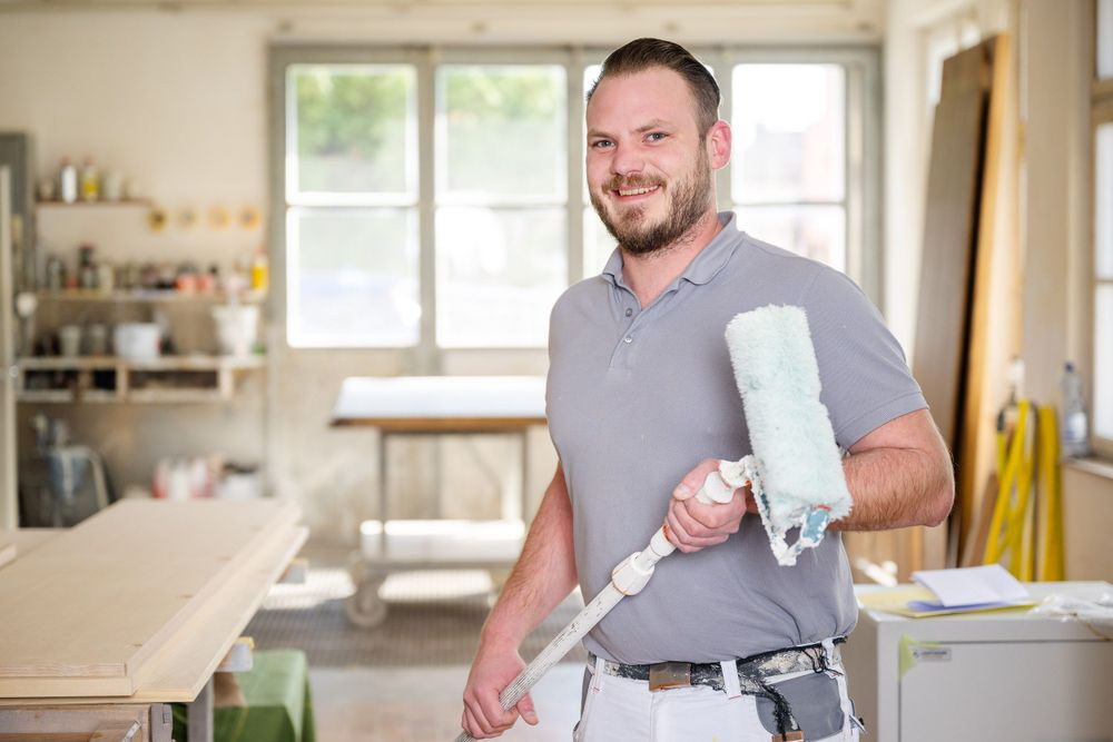 Person holding equipment while standing in bright, organized workshop setting.