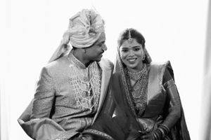 Black and white photo of a couple in traditional attire on their wedding day, smiling at each other with joy and elegance.