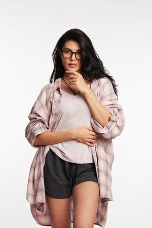 Jacqueline in a beige oversized jacket over a crop top and black shorts, posing confidently against a plain white background.