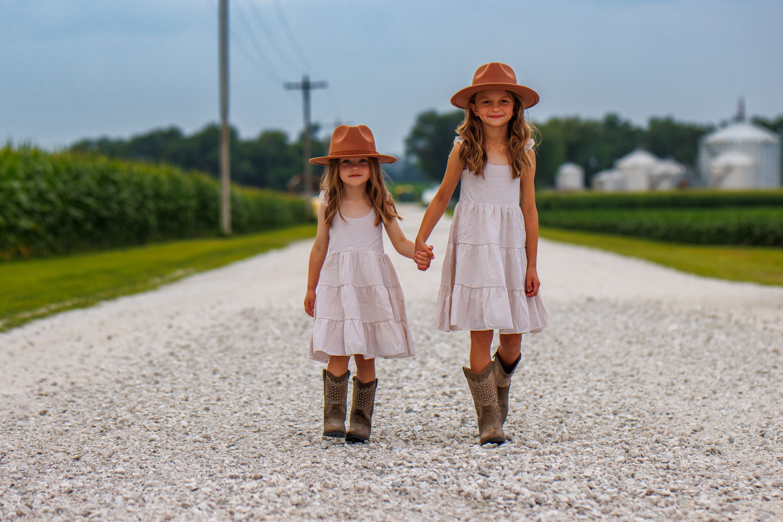 Series of photos taken on a gravel country road with orange sun hats and flowing dresses.