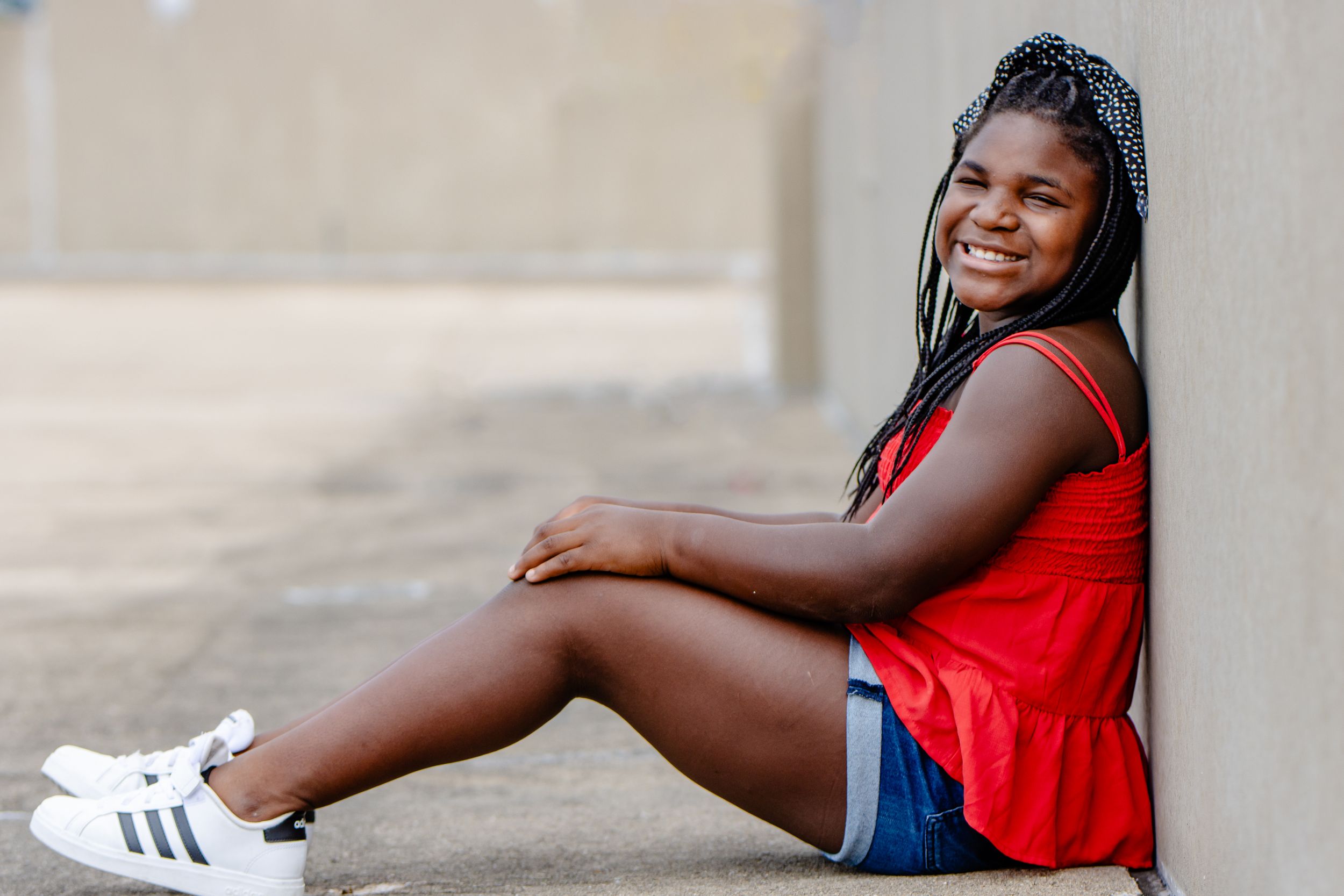 Casual portrait series against a concrete wall showcasing red athletic wear and sneakers.