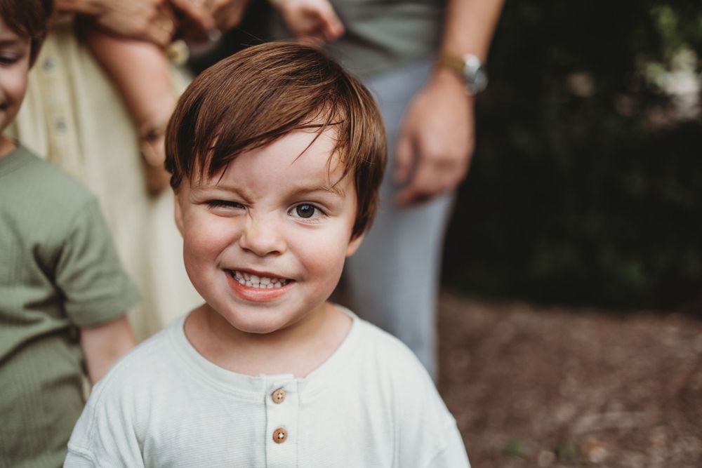 A close-up portrait of a young child with short brown hair smiling at the camera.