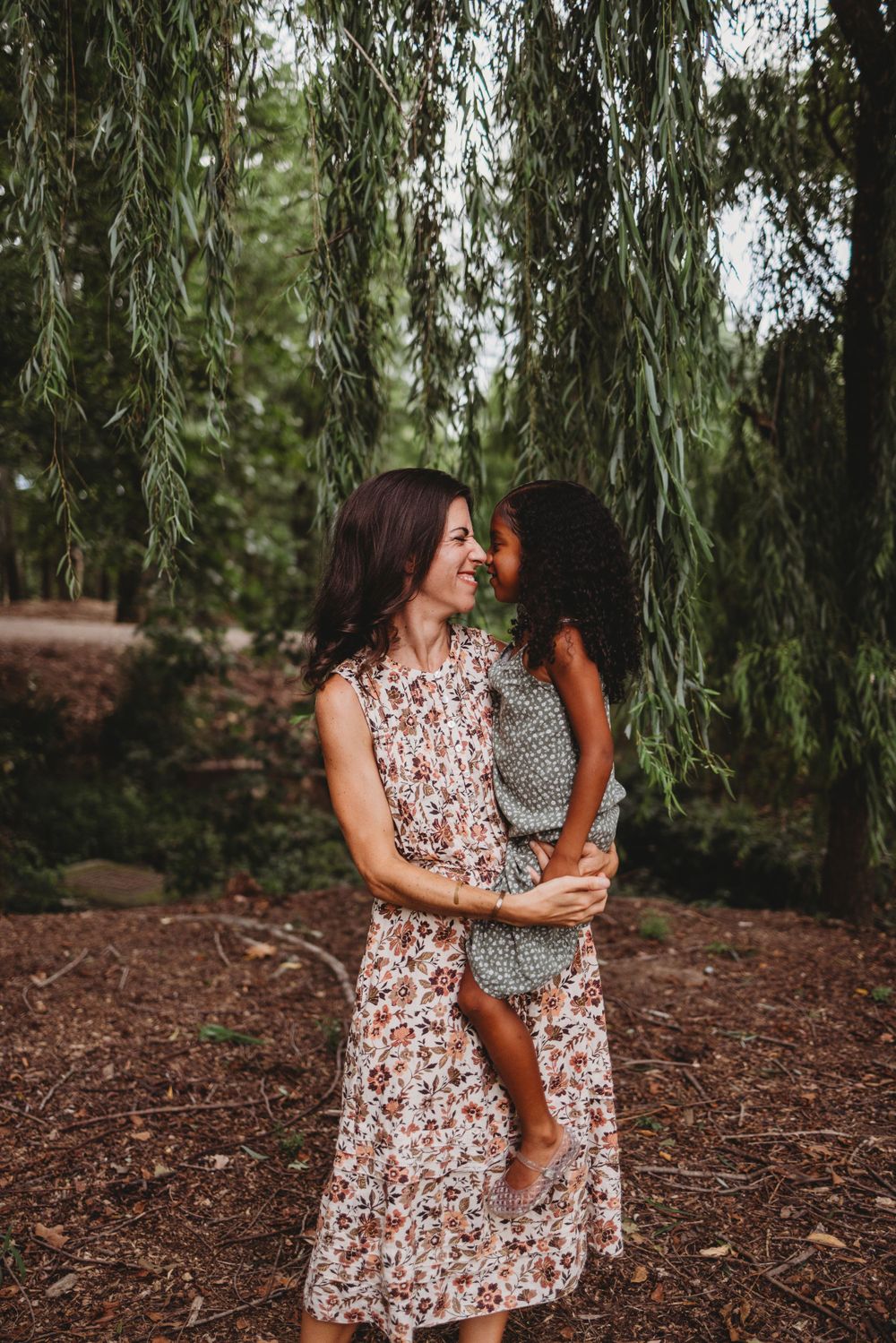 A tender moment between two people under drooping willow tree branches.