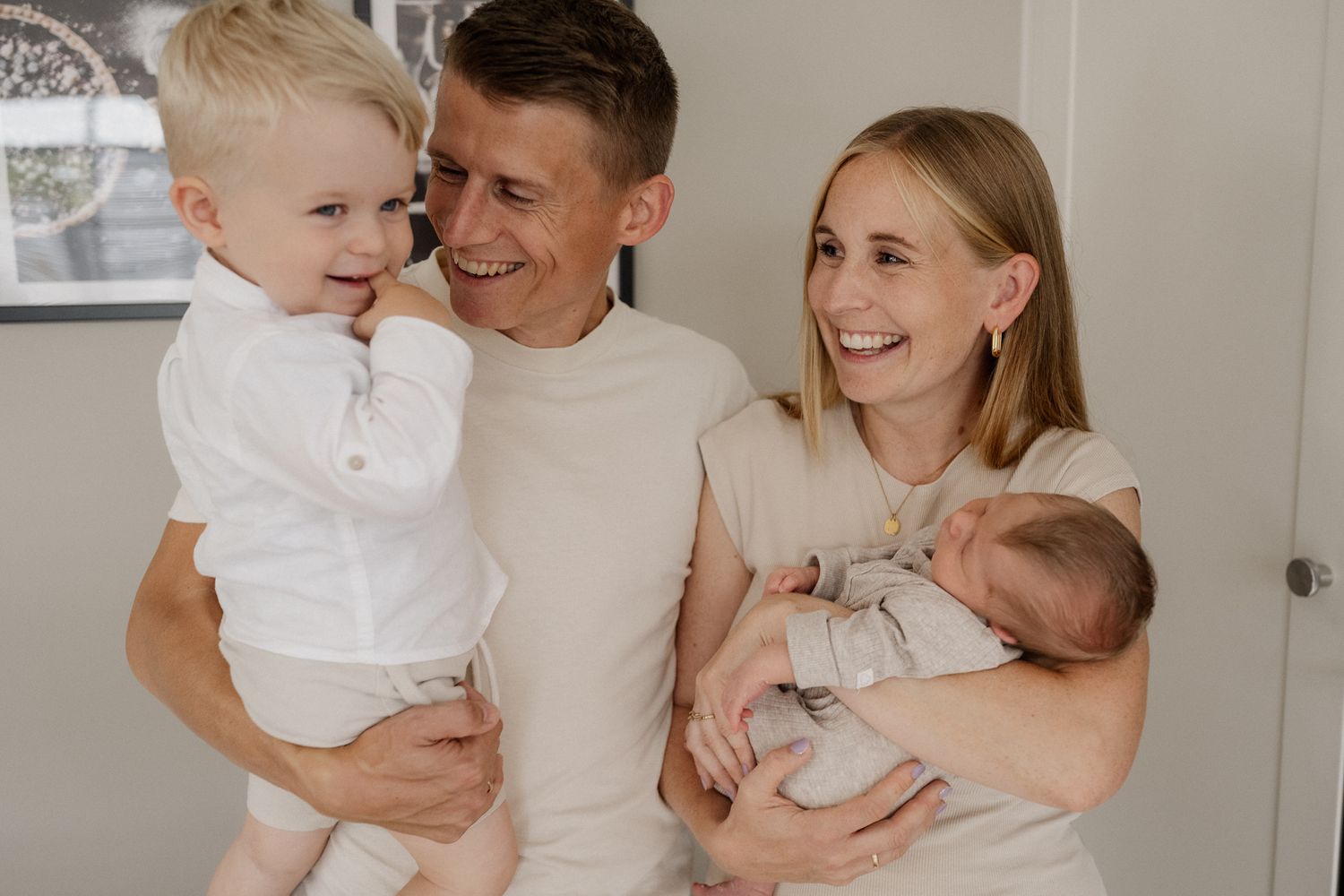 Happy family enjoying tender moments together at home in matching white and neutral outfits.