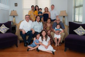 Extended family group portrait with grandparents, parents, and children gathered in a living room.