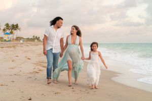 Happy expecting family walking together along a sunny beach.