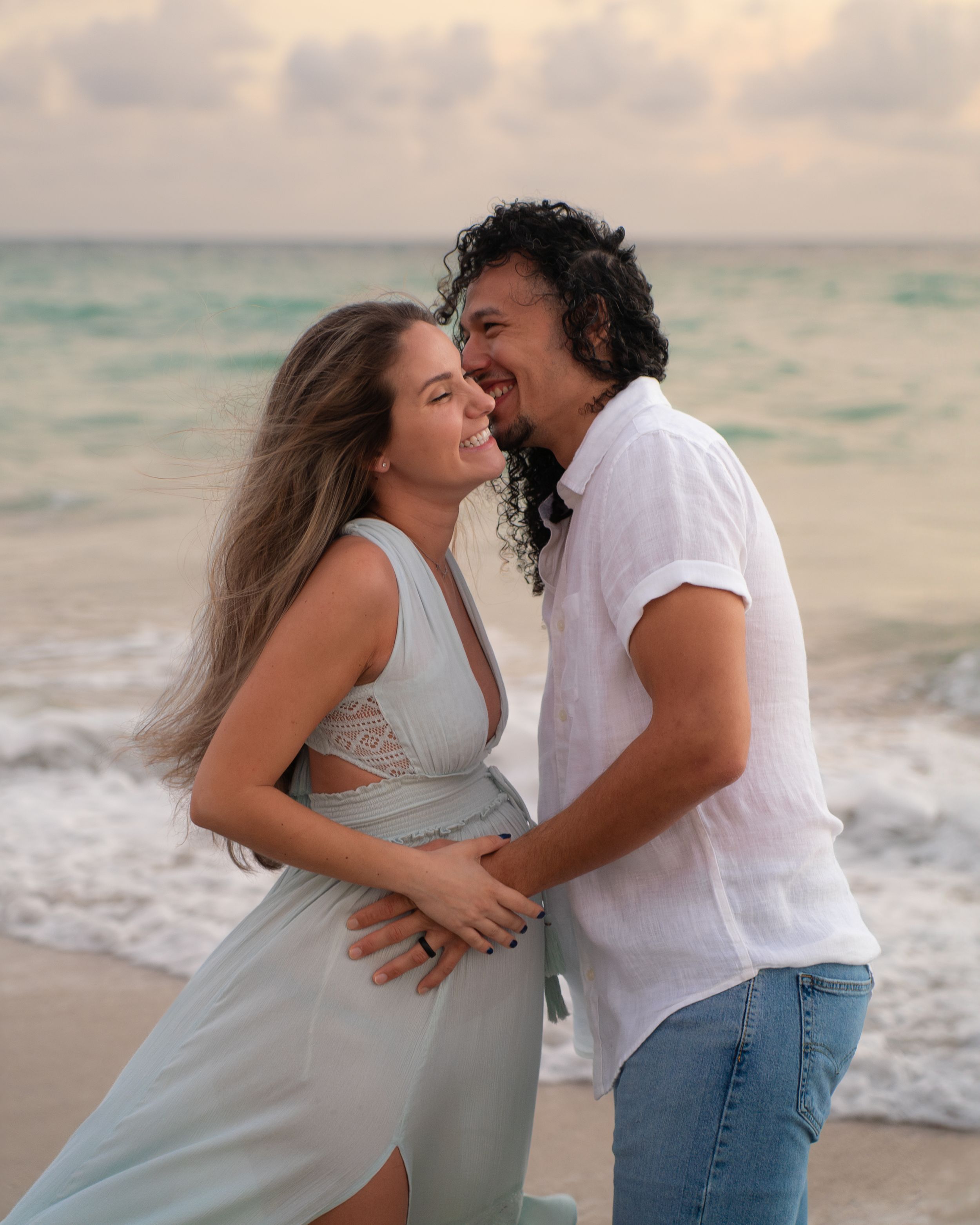 Couple sharing a tender moment on the beach at sunset.
