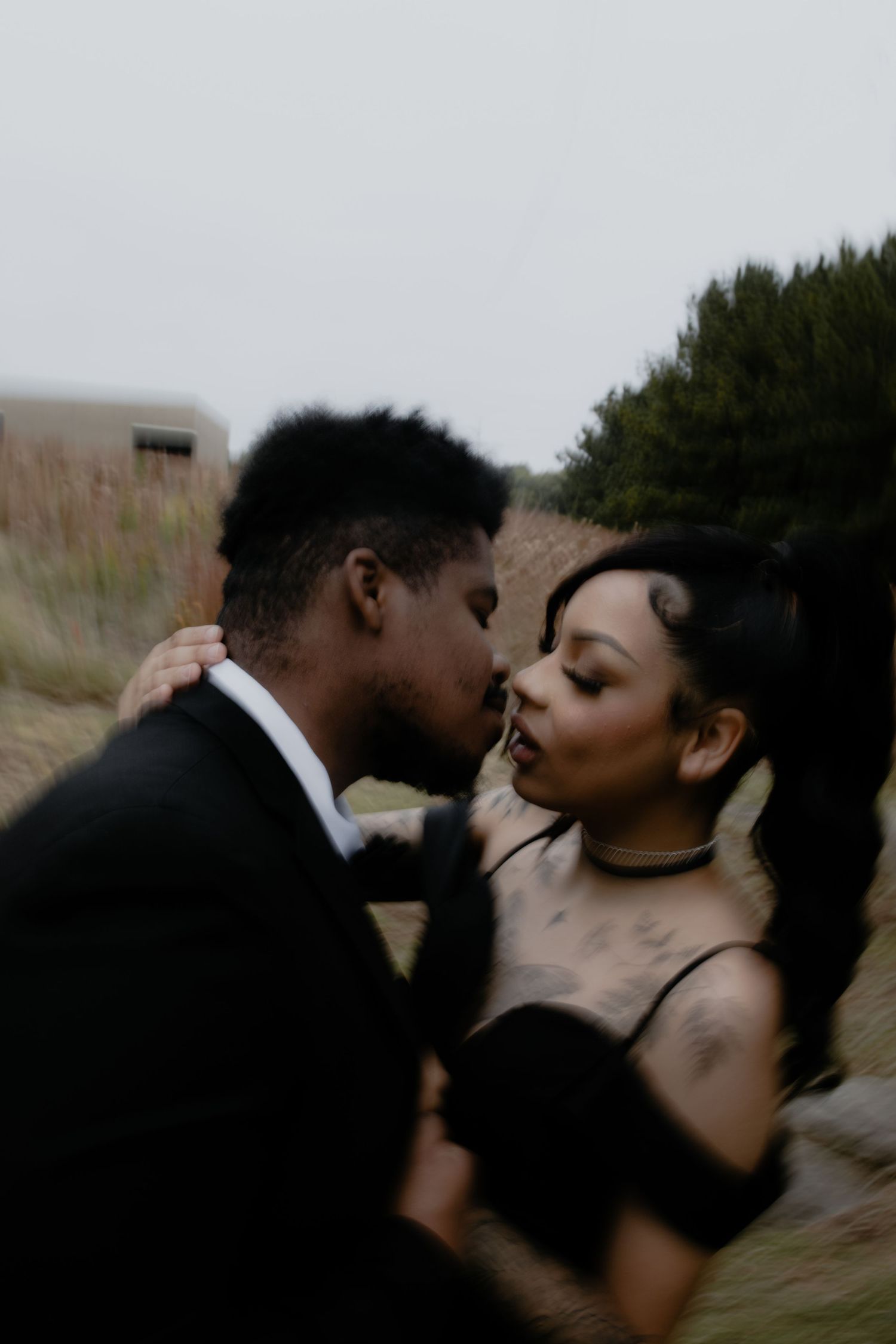 Intimate portrait of a couple in formal attire against a natural backdrop.