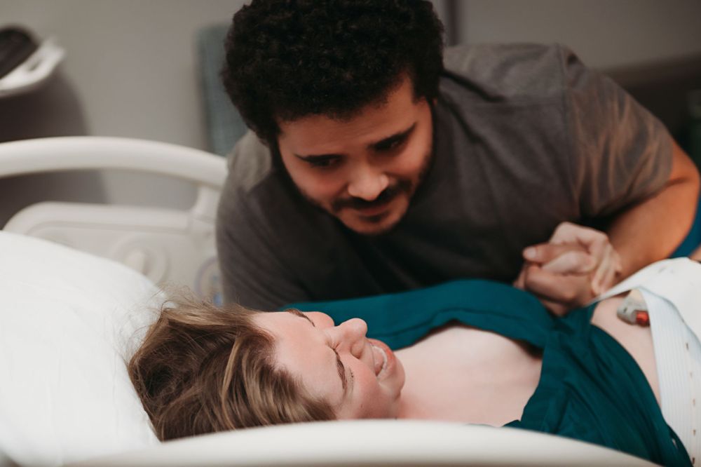 A couple shares a joyful moment together while mom gives birth.