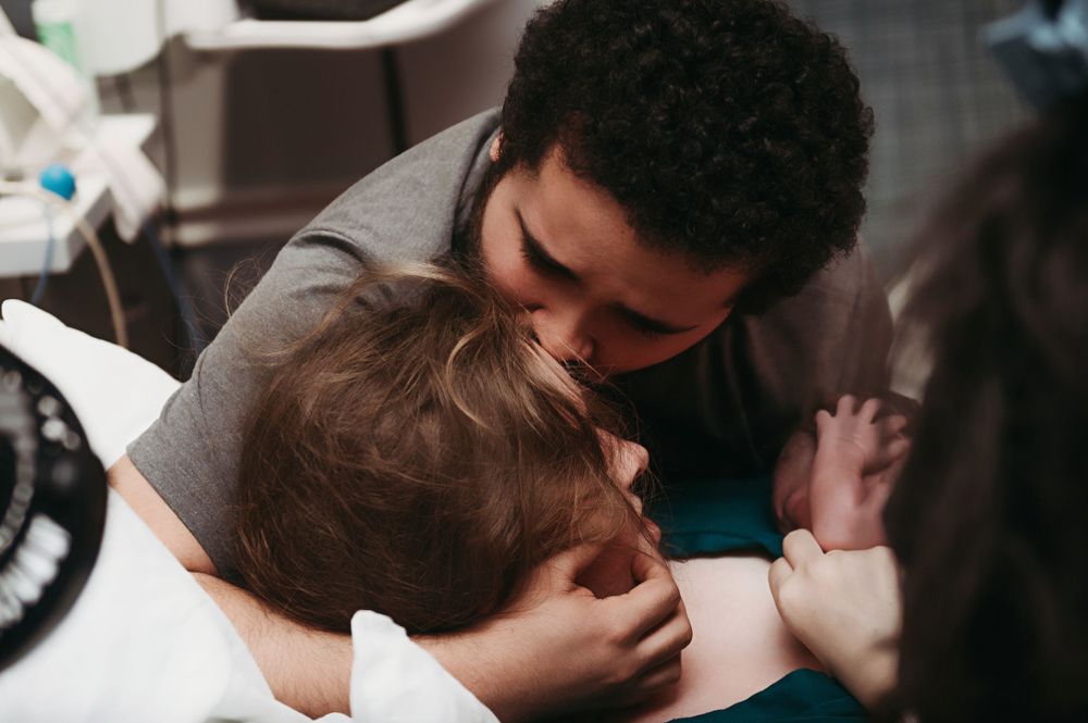 A tender moment captured as husband kissing his wife's head after she gave birth.