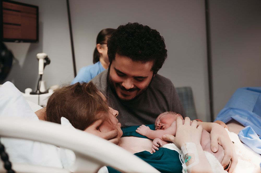 A heartwarming moment in a hospital room as a newborn baby is held and admired.