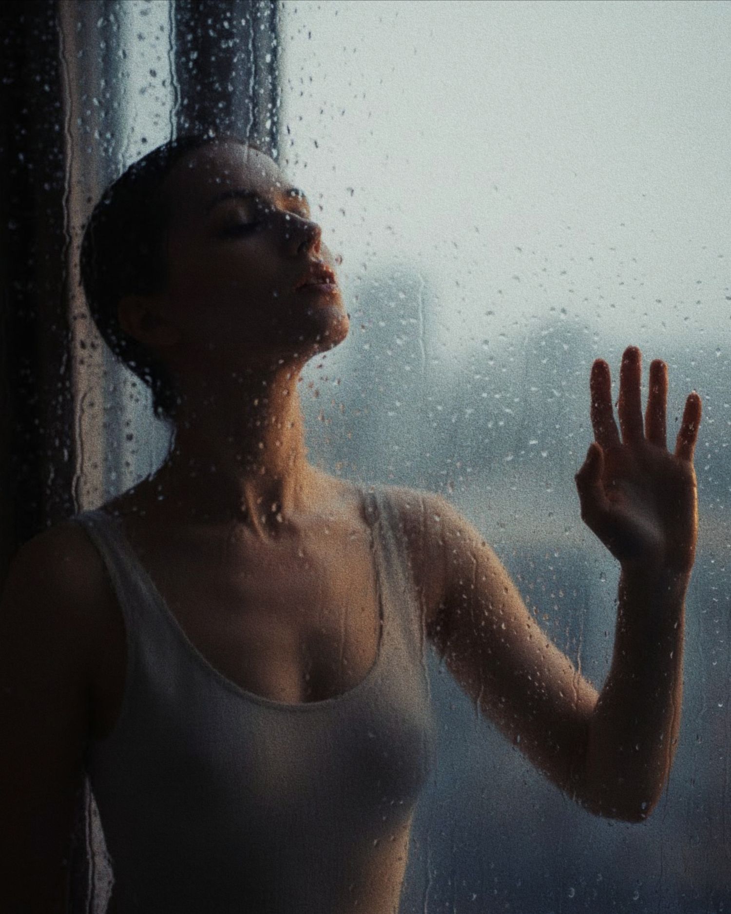 A silhouetted figure presses their hand against a rain-streaked window pane in moody atmospheric lighting.