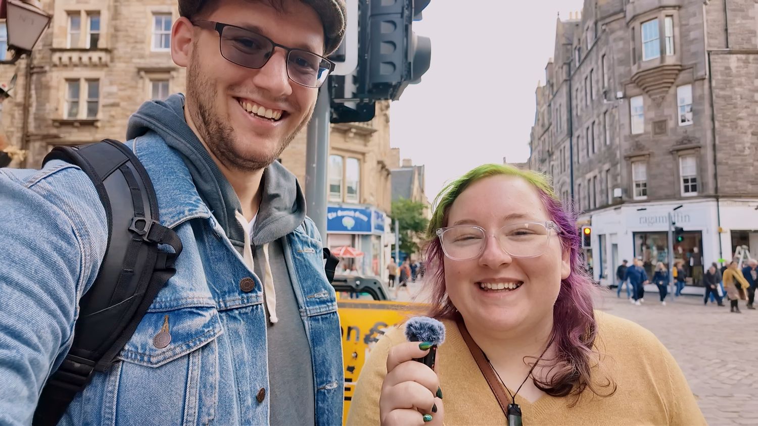 Two friends share a fun moment on a historic stone street with ice cream cones in Edinburgh.