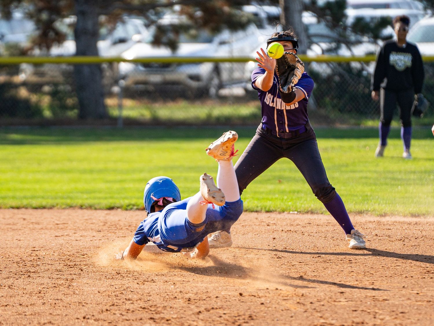 Two softball players collide at second base during an intense gameplay moment.
