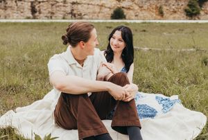 couple sinting on blanket in field with cliffs behind them