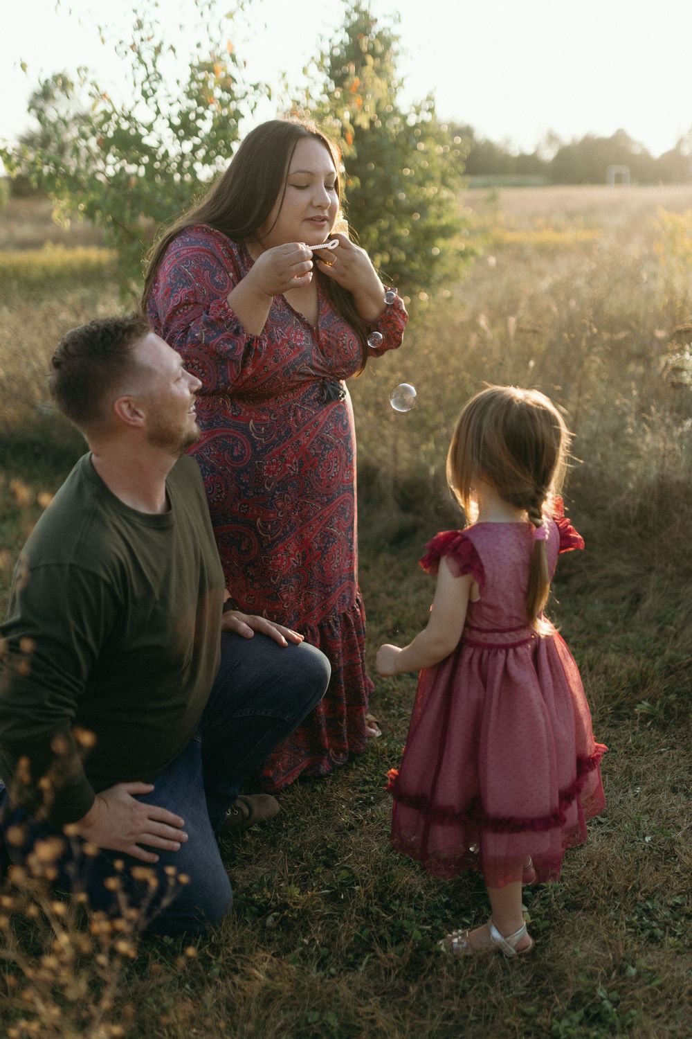 A candid family moment outdoors with bubbles at sunset.