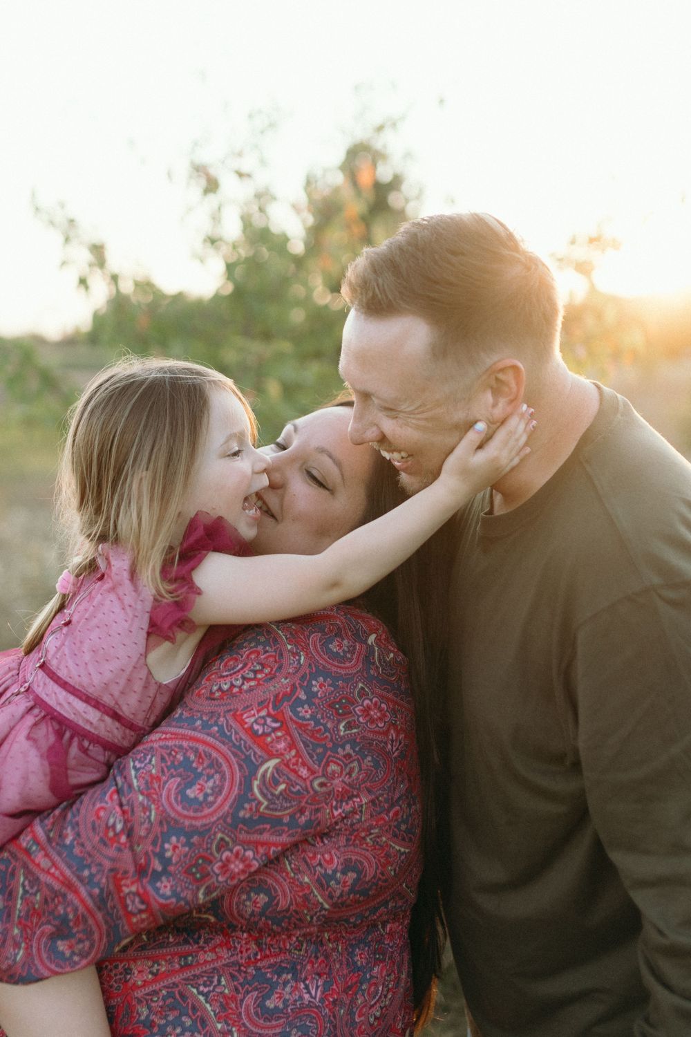 An intimate family moment captured during golden hour in a field.