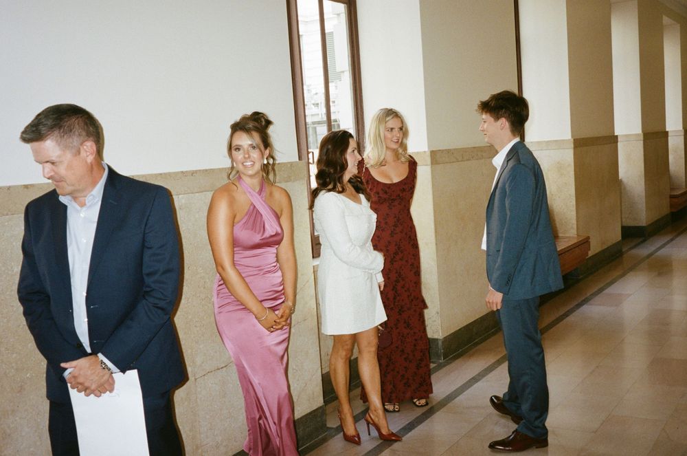 Group in formal attire standing in hallway before event.