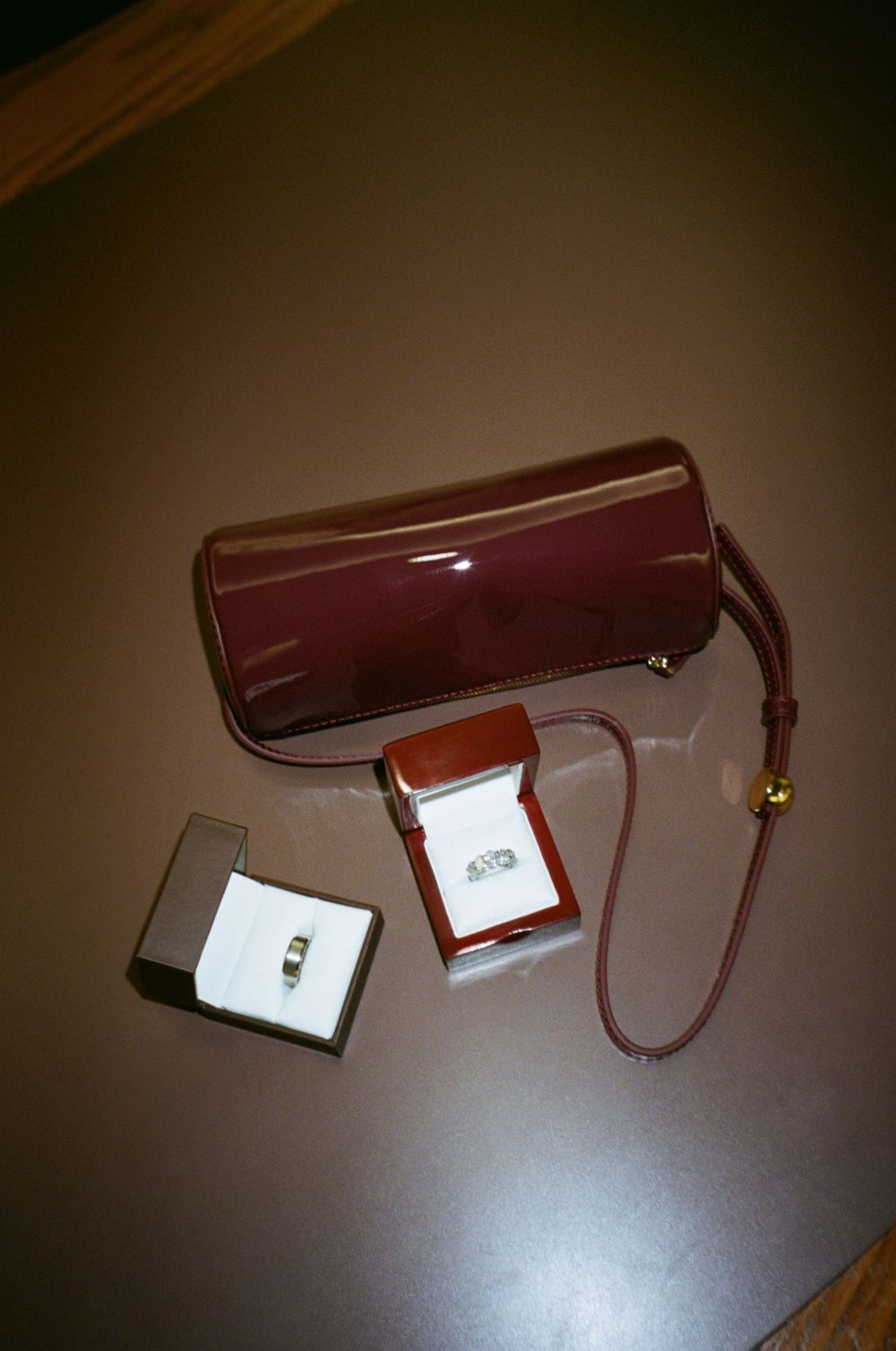 Wedding rings and jewelry boxes displayed with burgundy handbag.