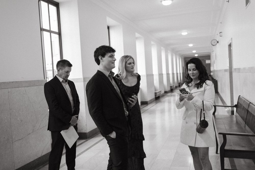 A group gathering in a bright white hallway having a casual conversation.