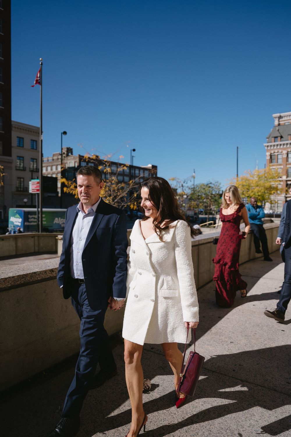 People walking along an urban sidewalk on a bright sunny day.