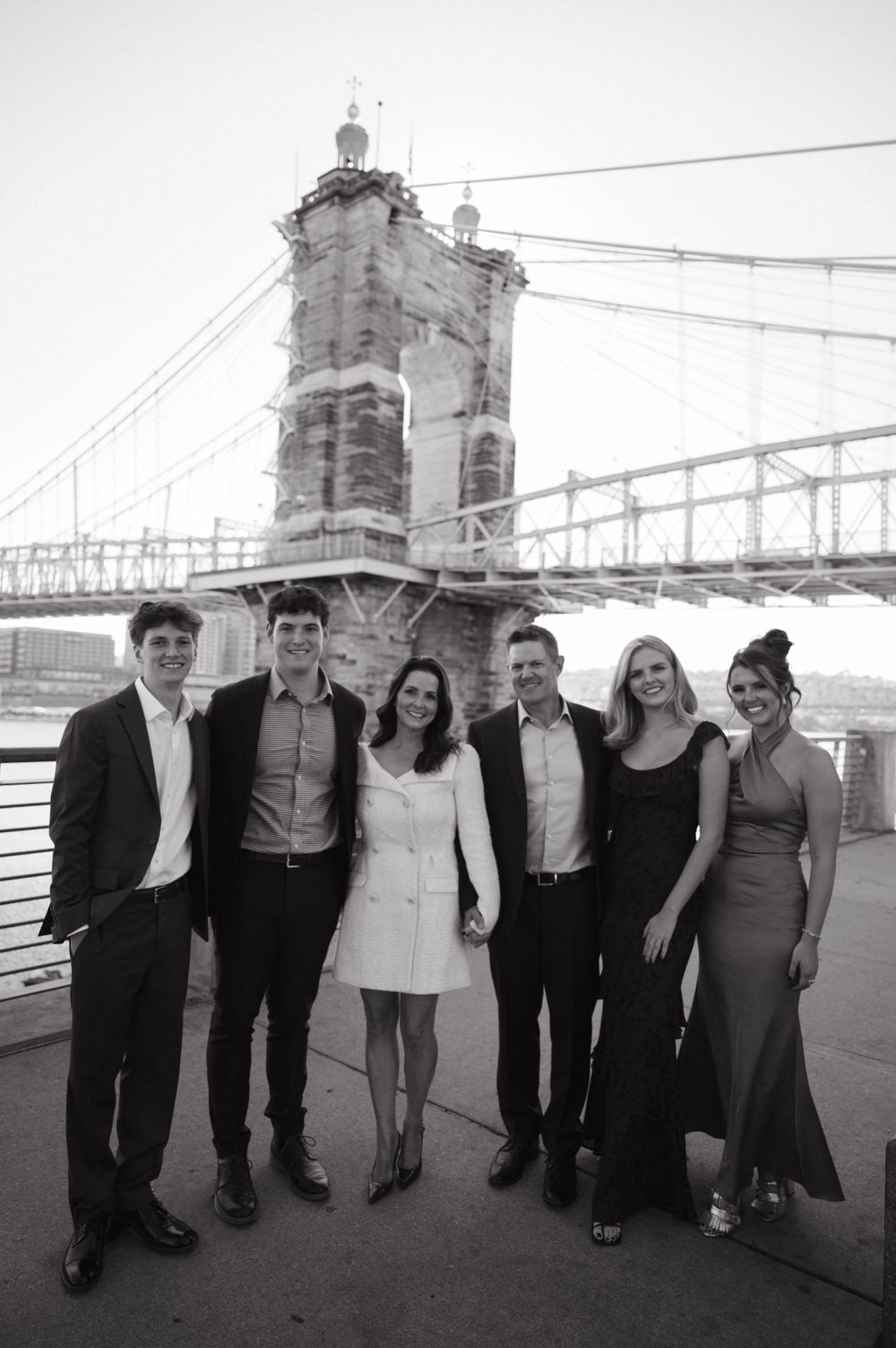 A formal group photo taken in front of the historic Roebling Suspension Bridge tower in Cincinnati.