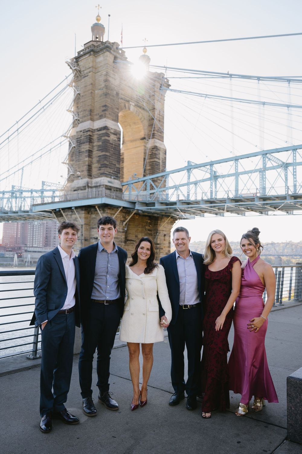 A group poses for a photo at sunset near a historic bridge tower with sunlight peeking through.