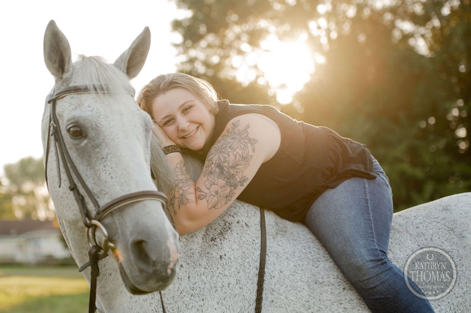 A person hugs a white horse while posing for a portrait at sunset.