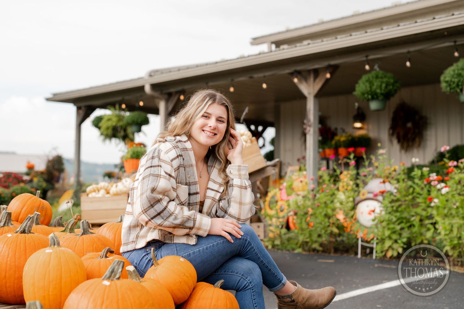 A fall portrait at a pumpkin patch with string lights and floral decorations.