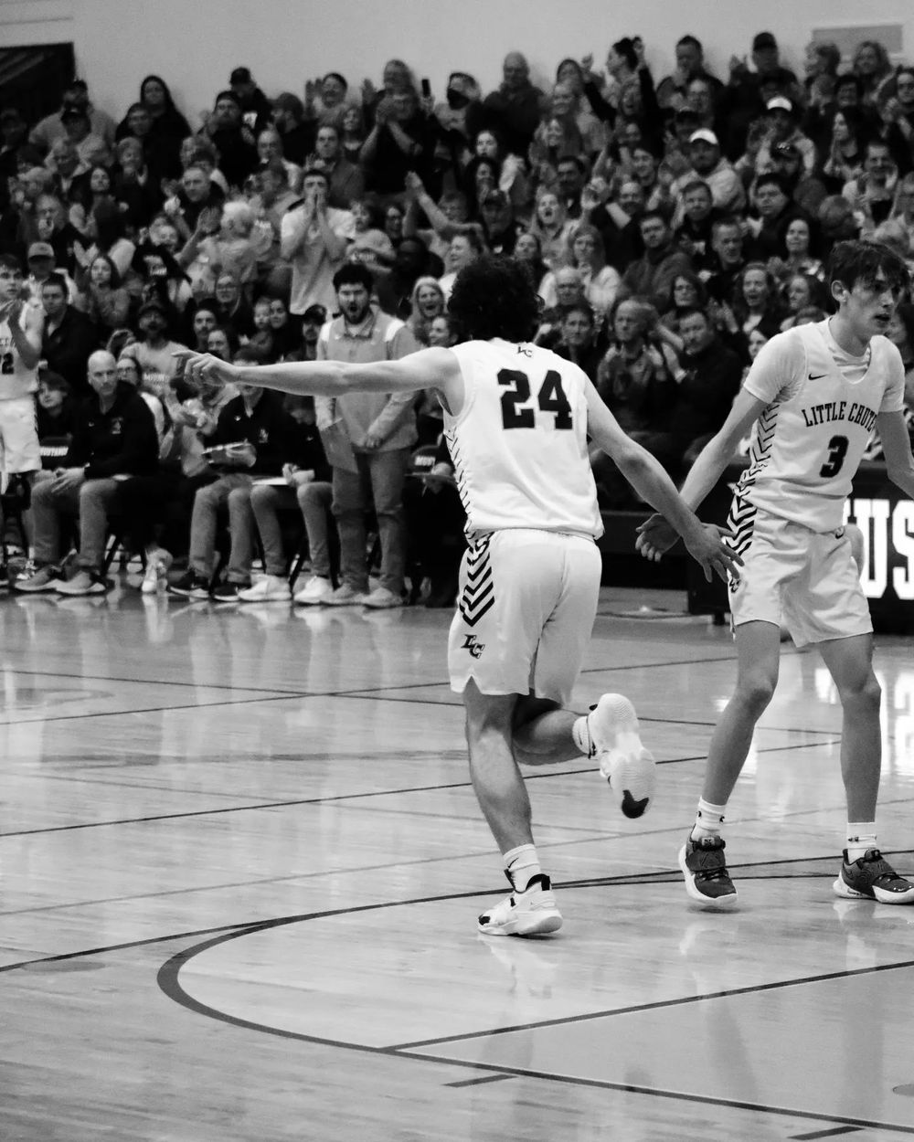 Basketball player in white jersey number 24 celebrates during game with crowd in background.