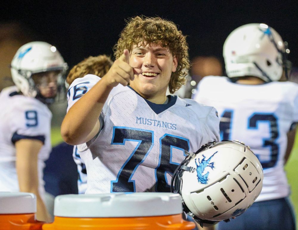 Football player in white jersey number 70 celebrates during nighttime game.
