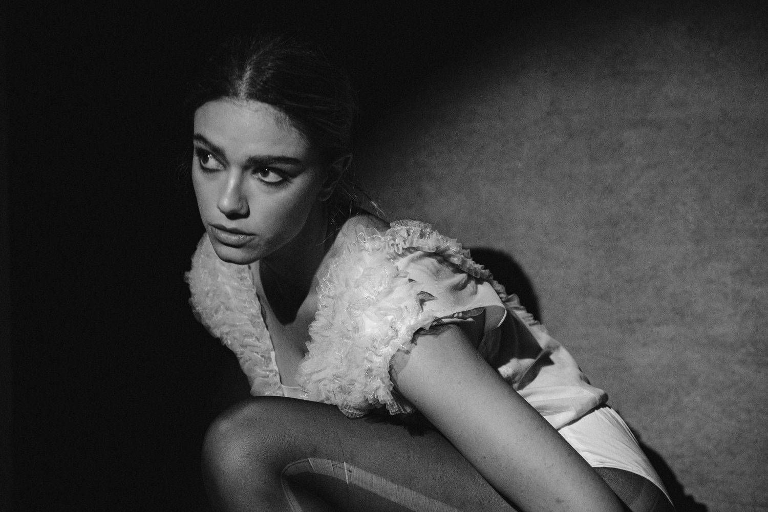 Artistic black and white fashion photograph featuring delicate lace dress details.