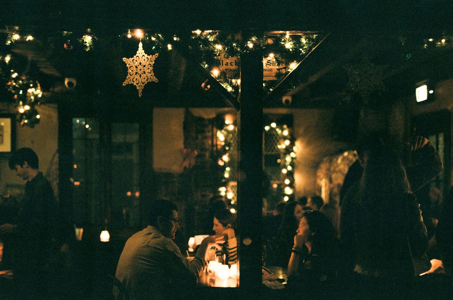 Cozy bar interior decorated with holiday lights and a glowing star ornament hanging from above.