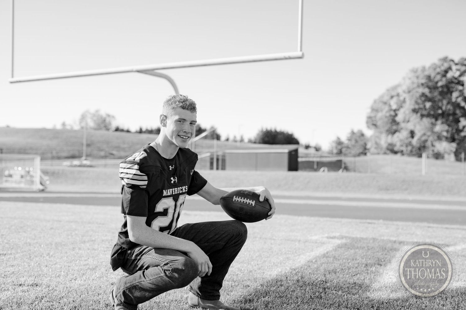 A football athlete crouches in black and white jersey number 20 on the playing field.