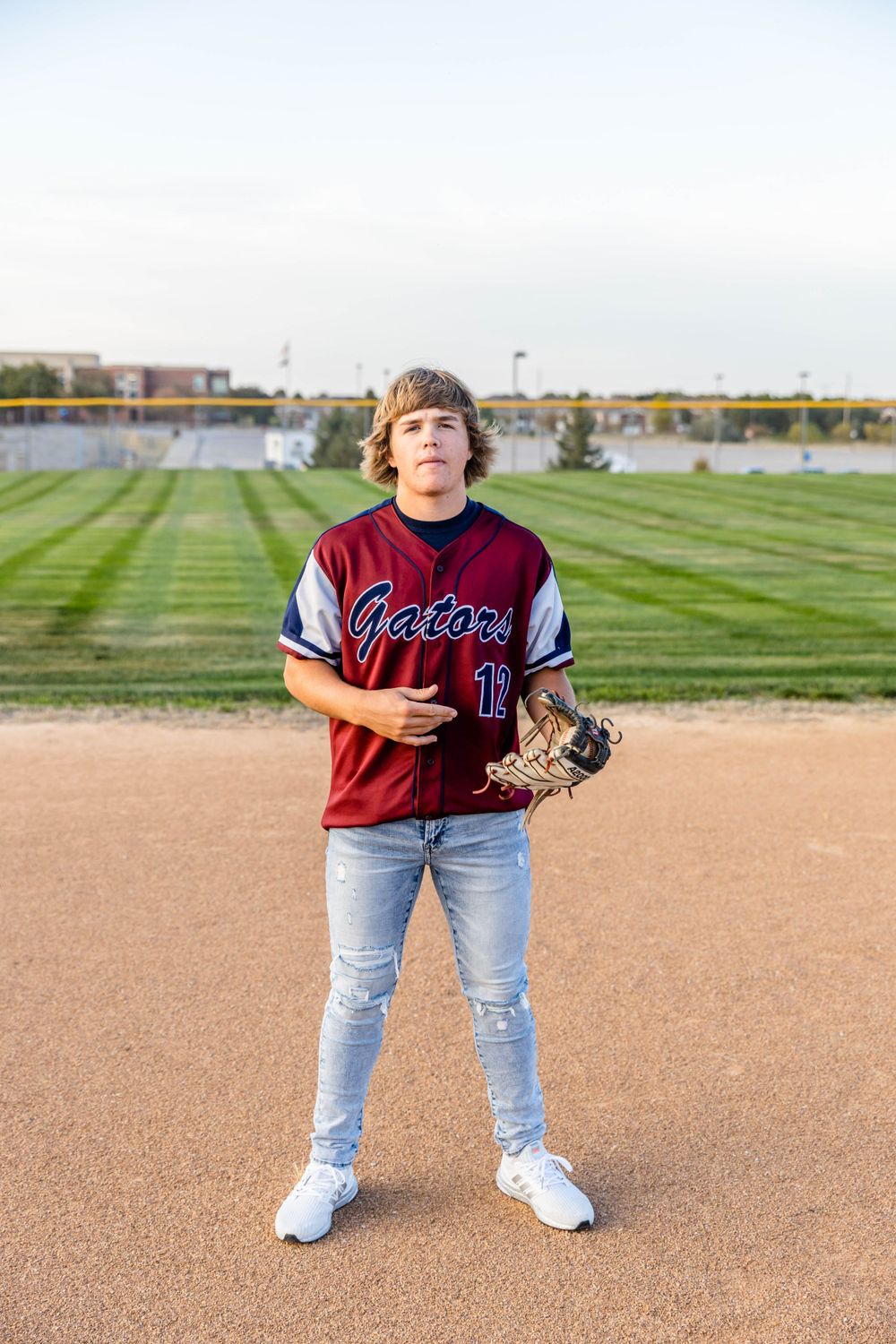 Baseball player in Gators uniform stands on field with glove.