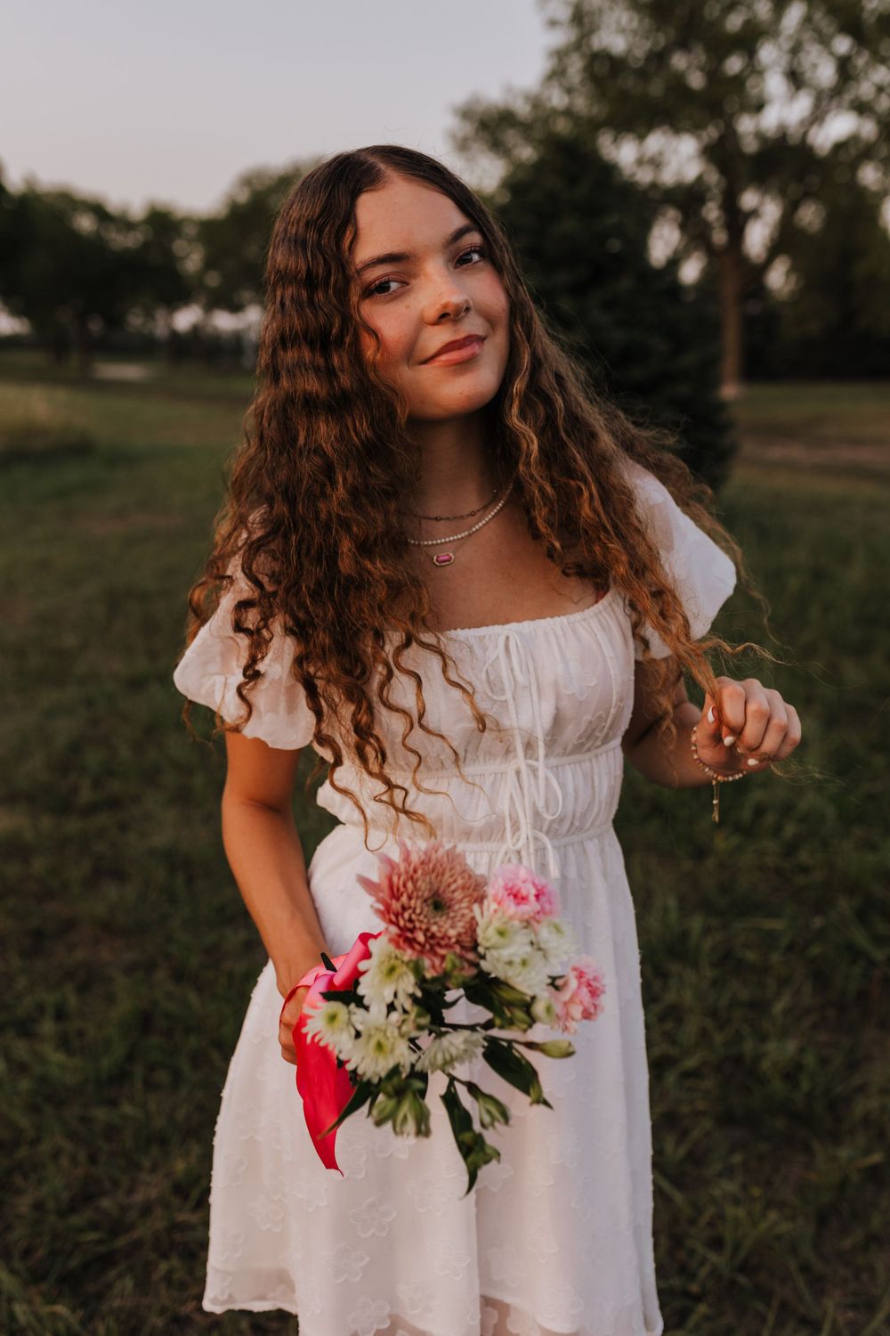 A summer portrait in a white dress holding a colorful bouquet at sunset.