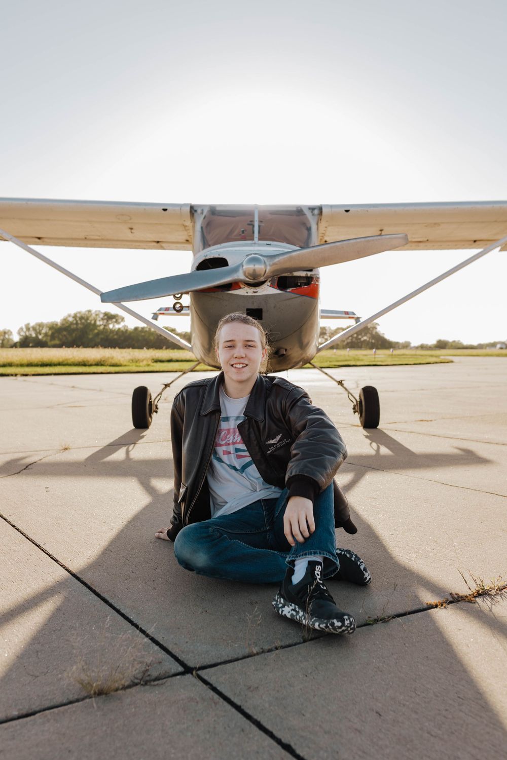 Person sitting under small aircraft wing on airport tarmac shown from multiple angles in series of photos.