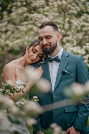 Tender moment between newlyweds surrounded by spring cherry blossoms.