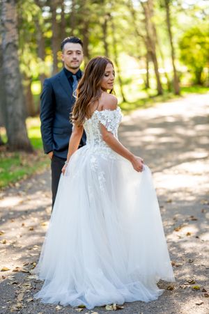 Ethereal wedding photograph showing detailed lace gown against forest backdrop.